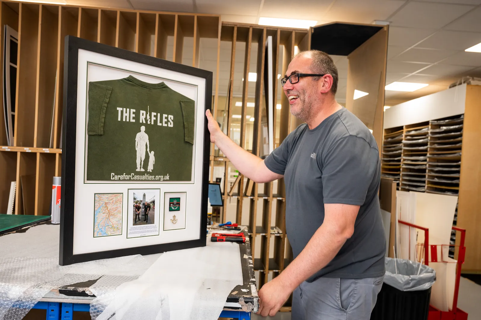 A member of the framing team holding a framed shirt