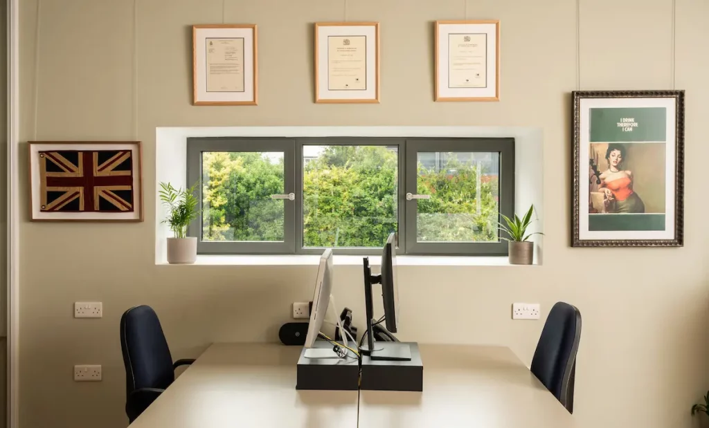 An office space with documents, a poster and a flag framed on the wall